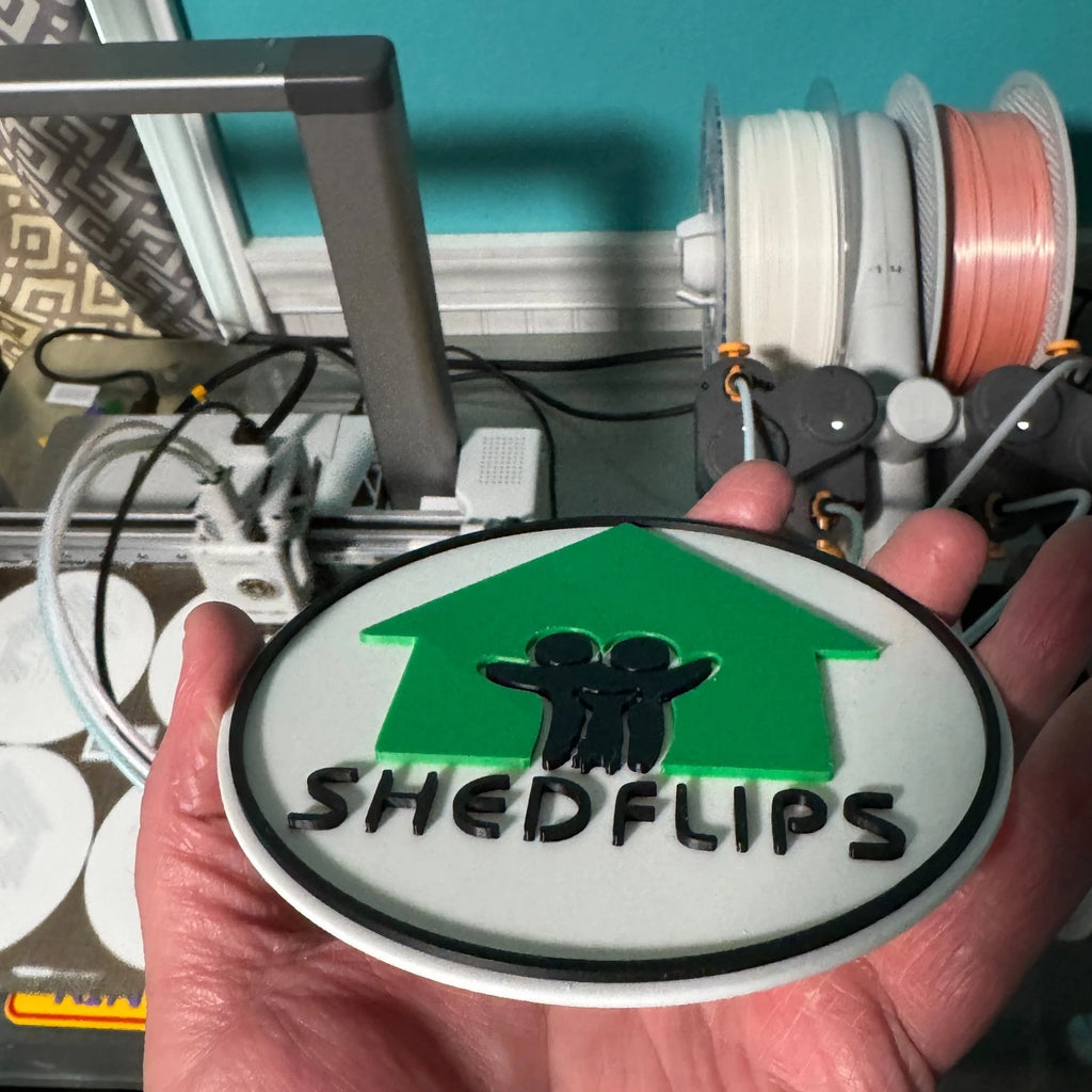 Shed Flips magnet held in front of the 3D printer that made it